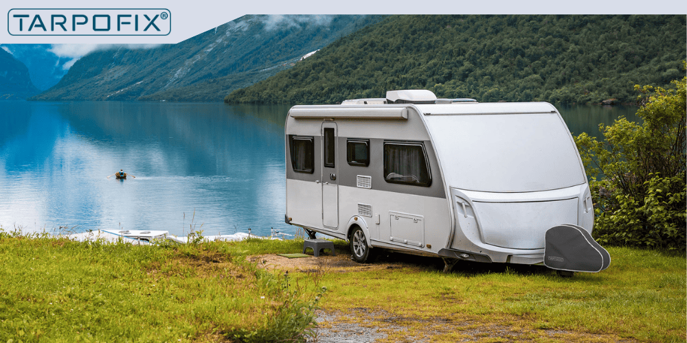 Ein Wohnwagen am See, der mit einer Deichselhaube von Tarpofix ausgestattet ist.